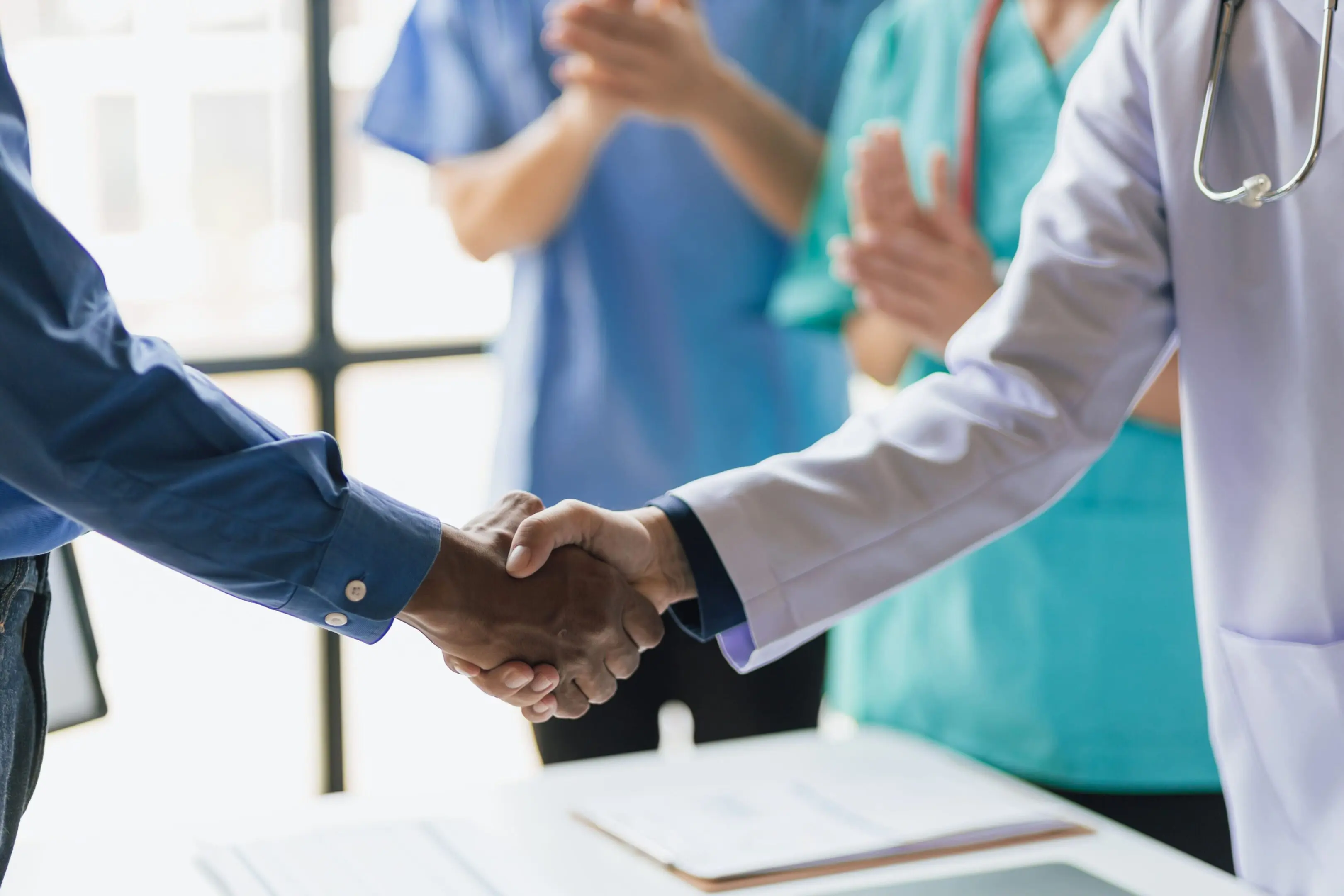 GettyImages-1498442493 Doctor and patient shaking hands, medical team applauding.